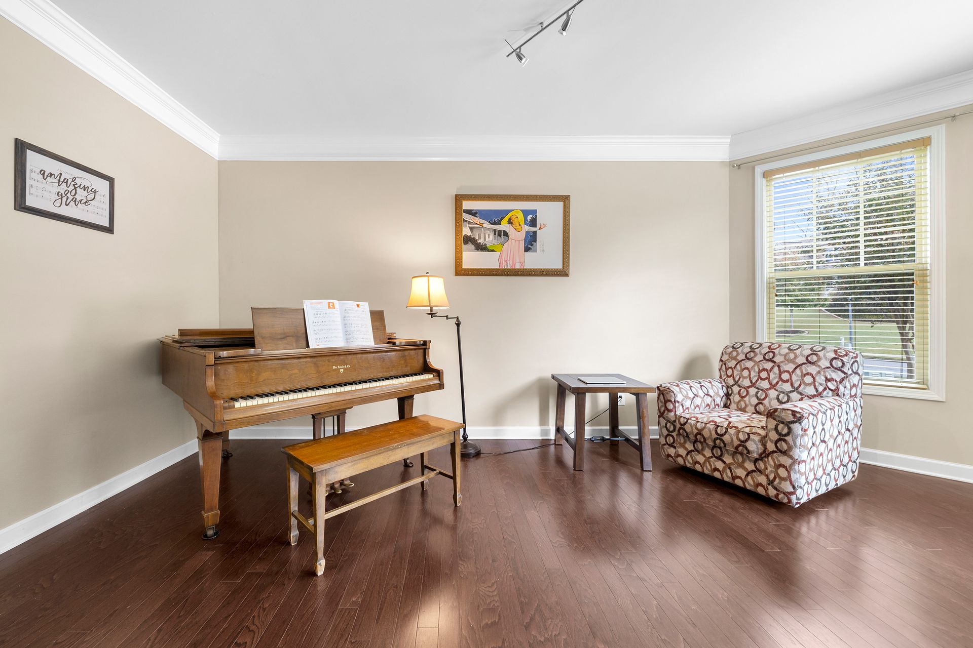 A living room with a piano , chair , table and lamp.
