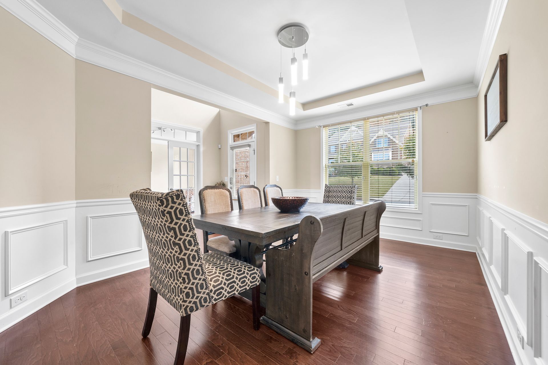 A dining room with a table and chairs and a large window.