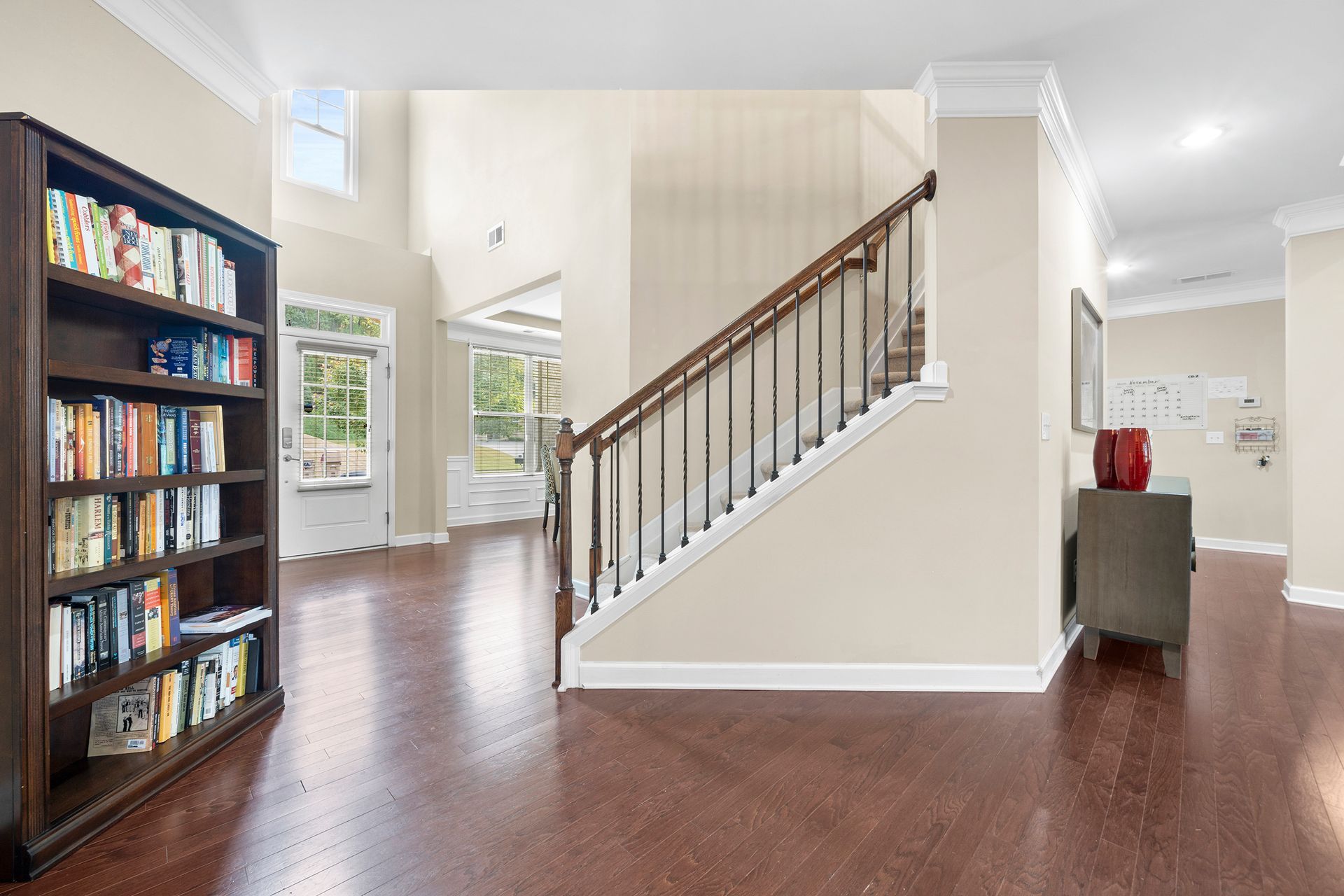 A living room with a staircase and a bookshelf filled with books.