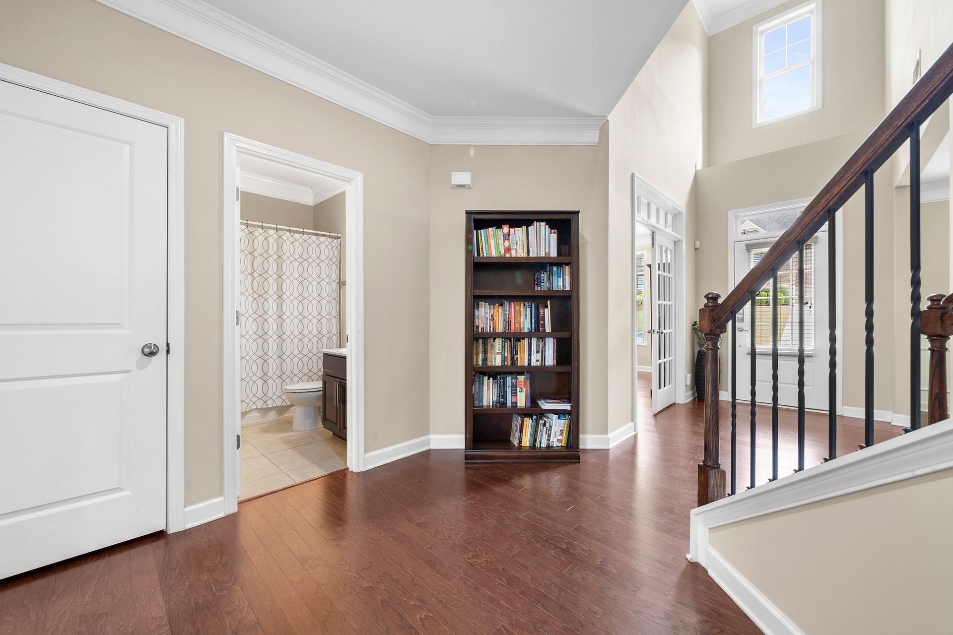 A hallway with a bookshelf and stairs in a house.