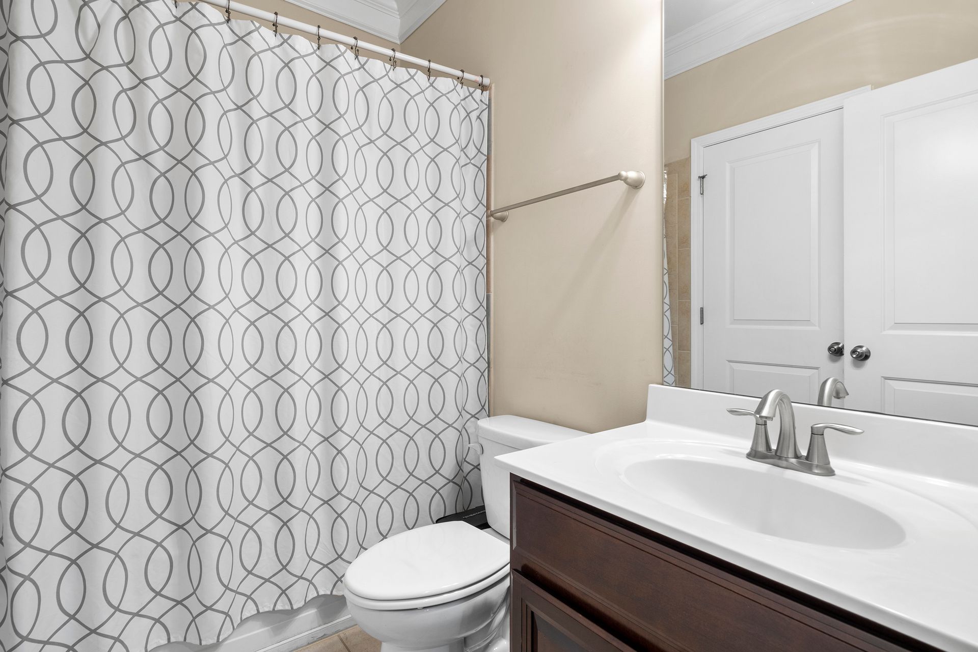 A bathroom with a toilet , sink , and shower curtain.