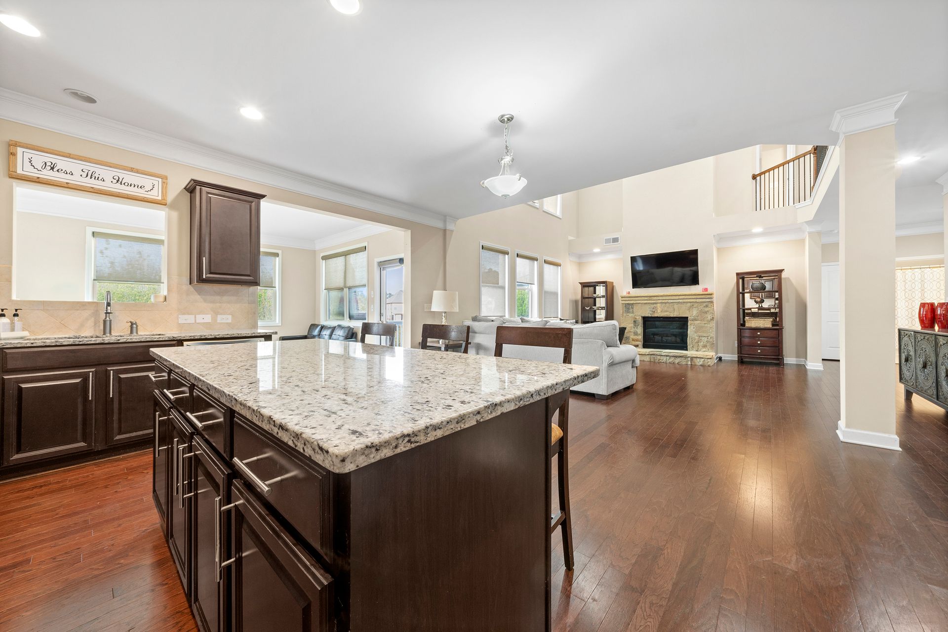 A kitchen with a large island and granite counter tops in a large house.