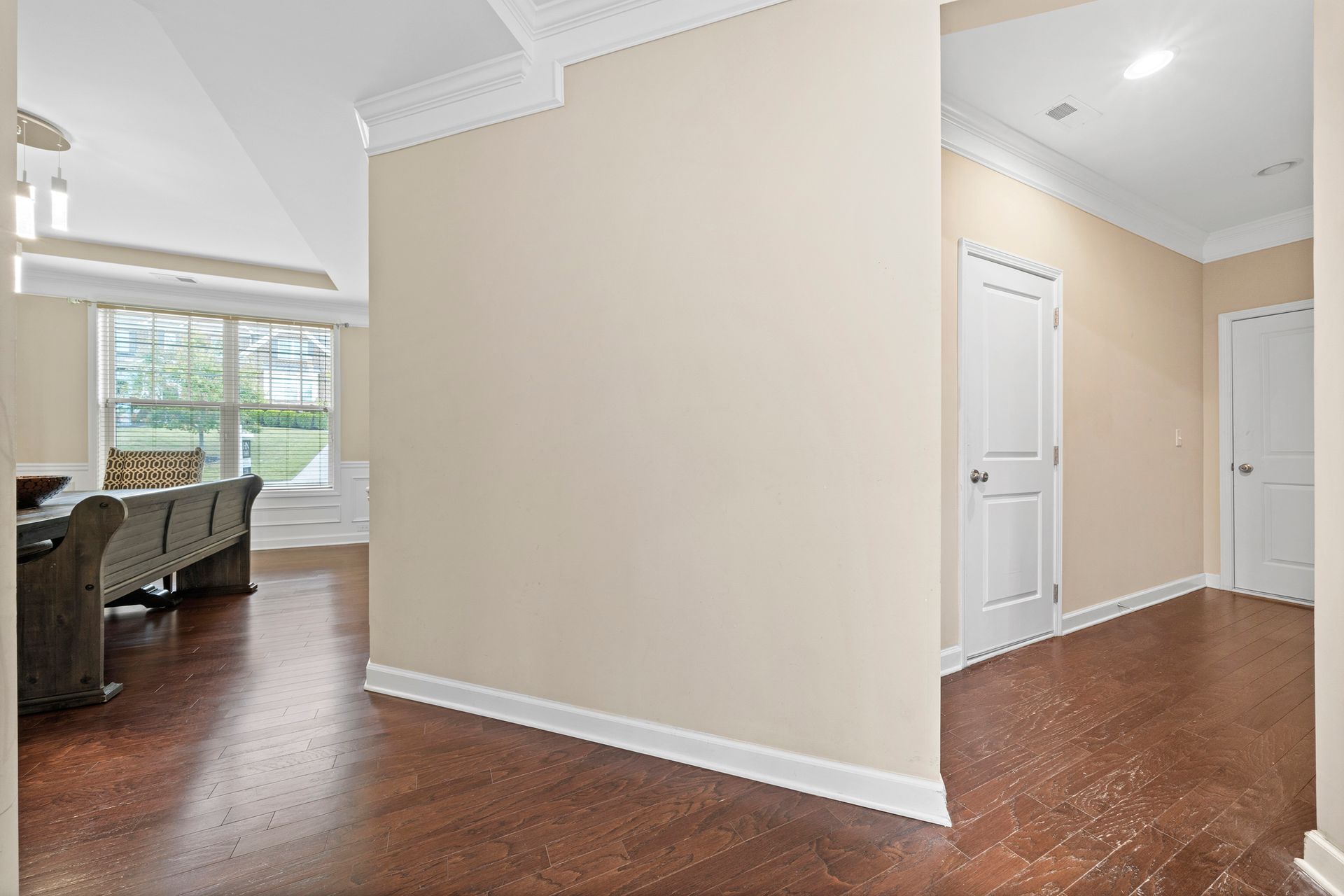 A hallway in a house with hardwood floors and beige walls.
