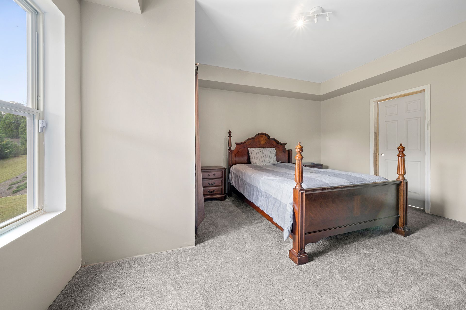 A bedroom with a bed , nightstand , and window.