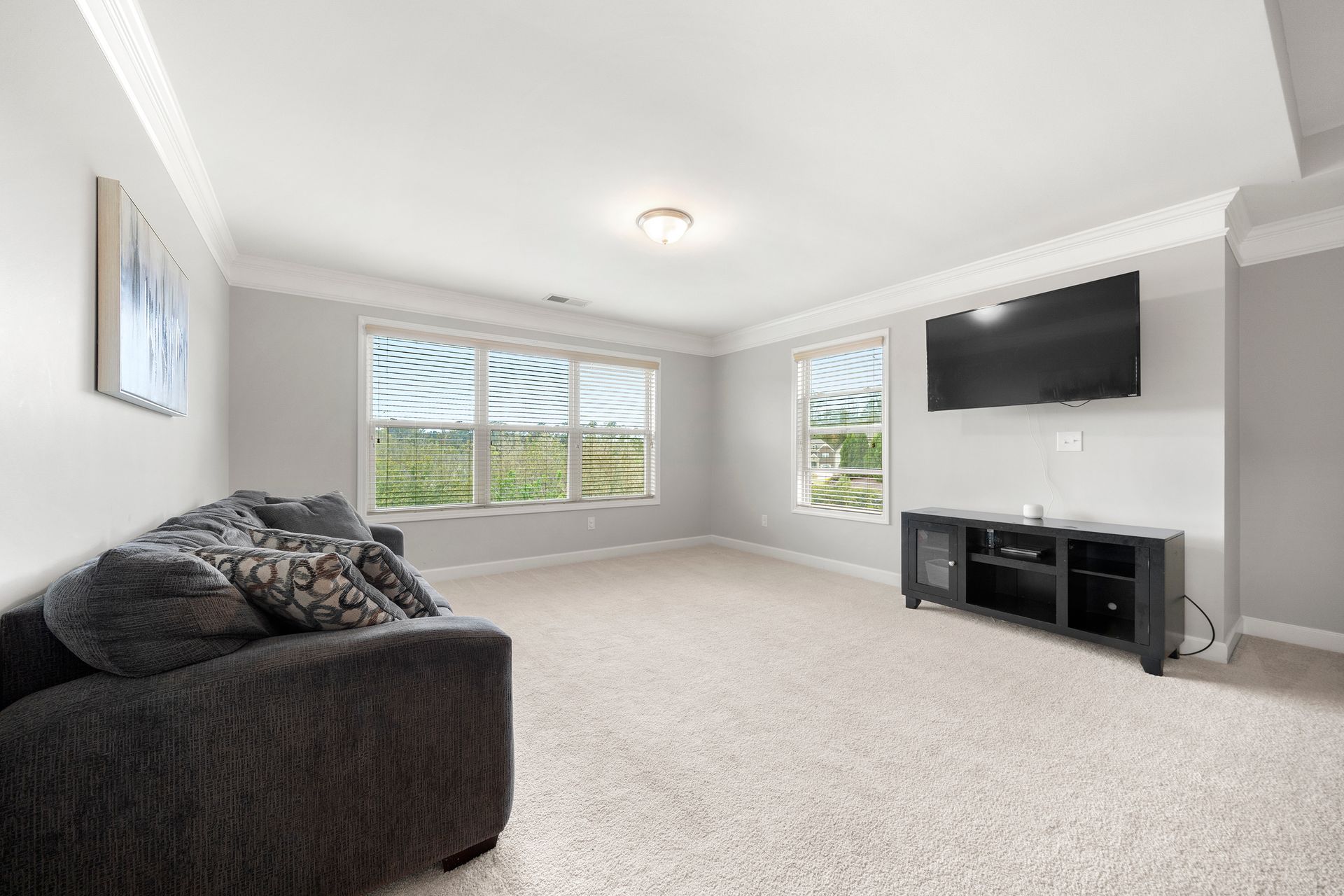 A living room with a couch and a flat screen tv on the wall.
