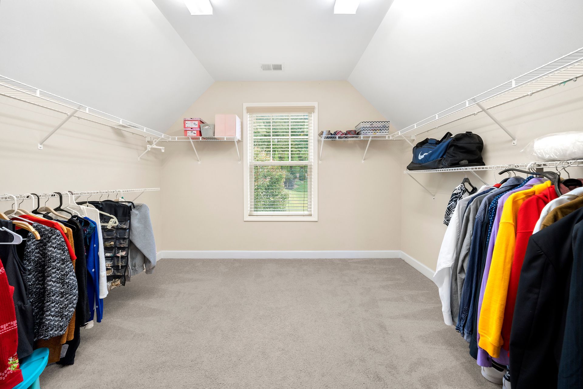 A walk in closet filled with clothes and a window.