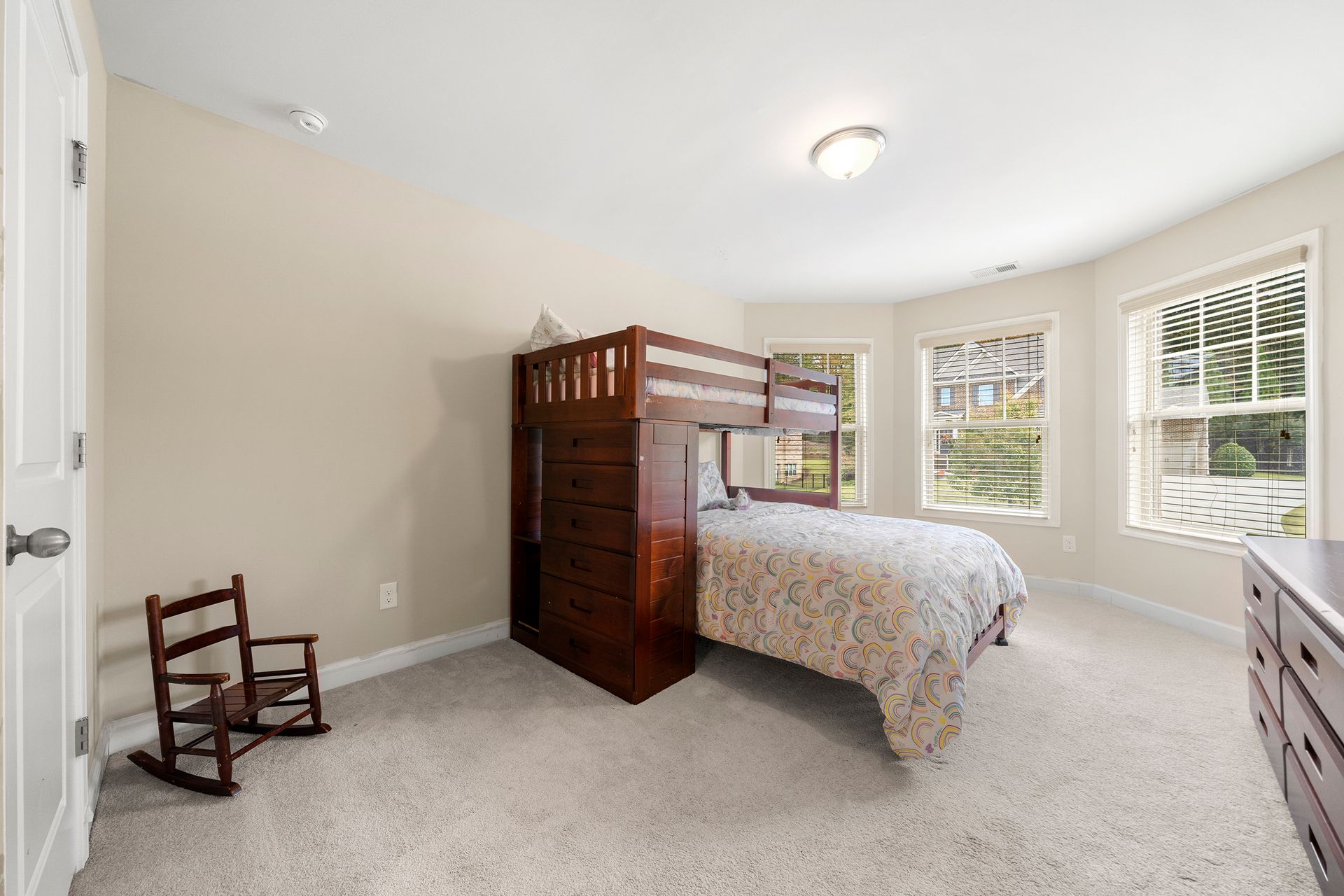 A bedroom with a bunk bed and a rocking chair.