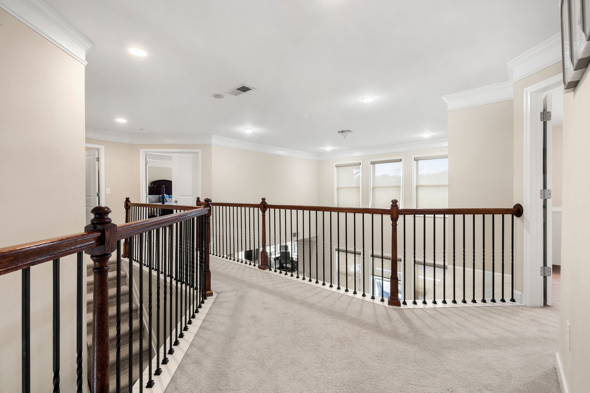 A hallway with stairs and a railing in a house.