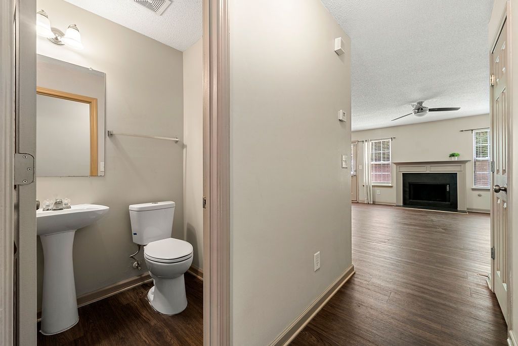 A bathroom with a toilet , sink , mirror and fireplace.