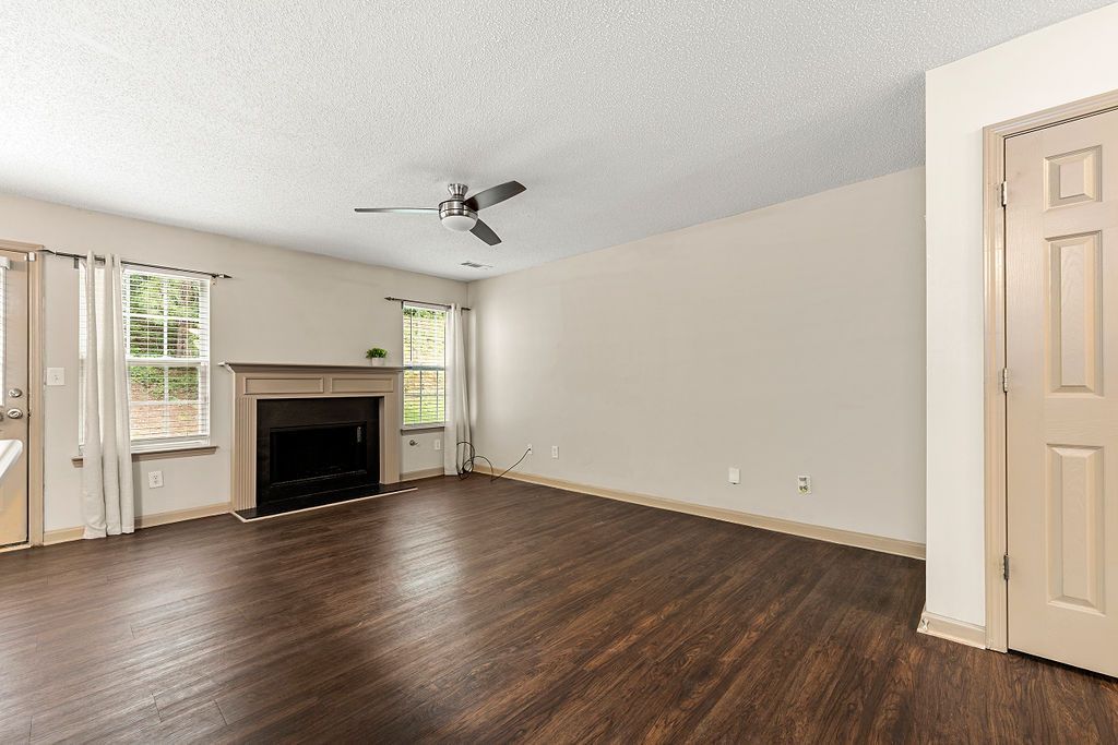 An empty living room with a fireplace and a ceiling fan.
