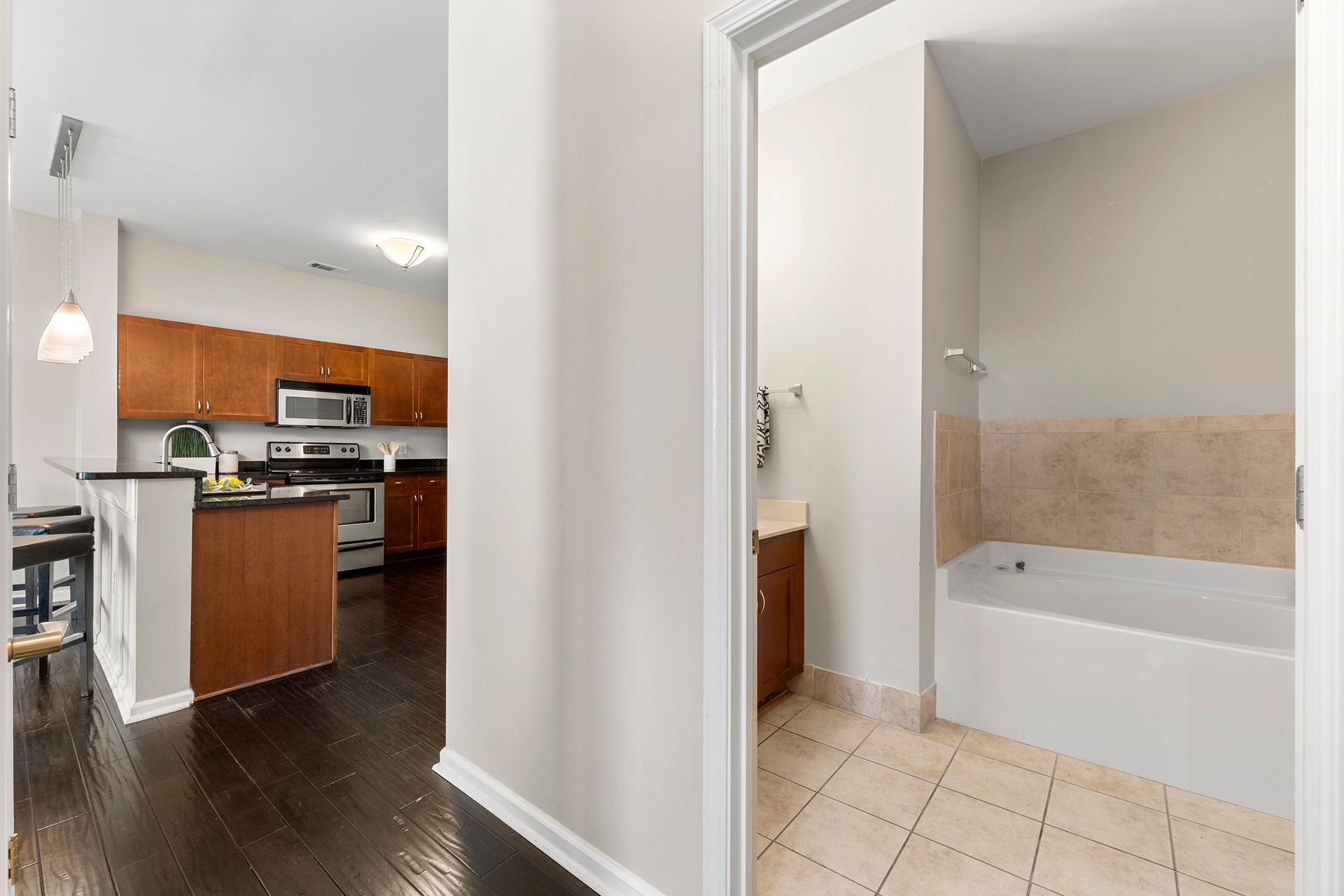 A hallway leading to a bathroom and kitchen in a house.