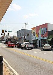 A row of buildings along a city street with cars driving down it.