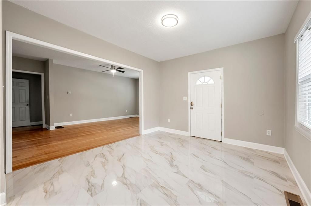 Empty living room with tiled floor, doorway, and white door.