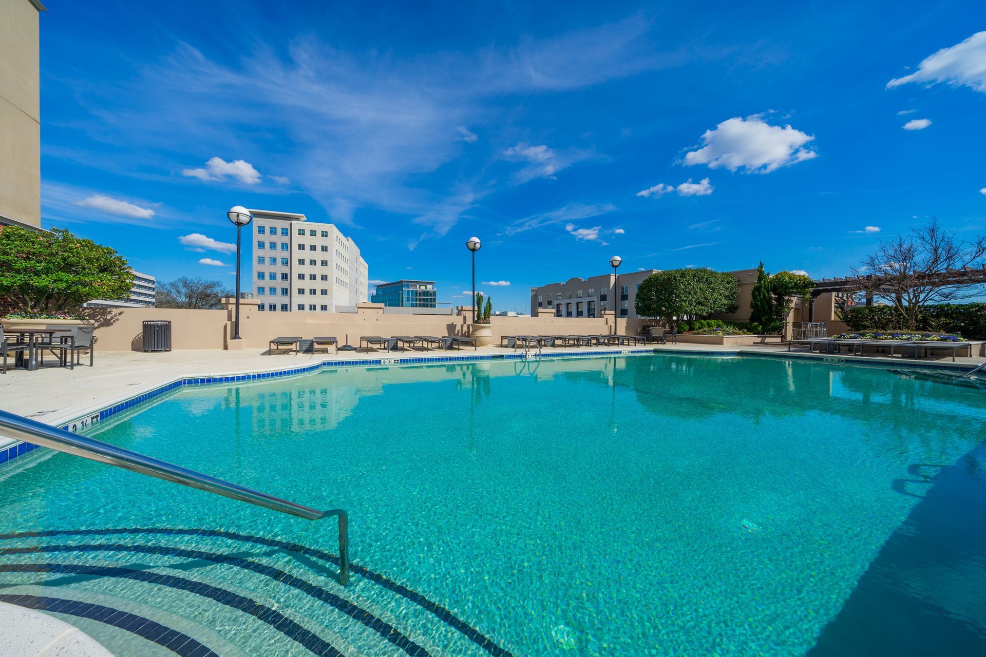 A large swimming pool with stairs leading to it and a building in the background.