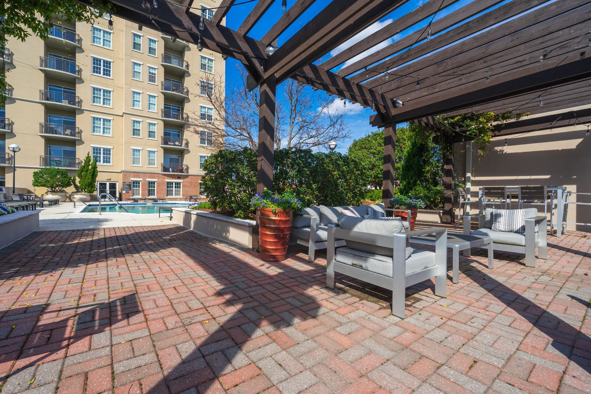 A patio with chairs and a pergola in front of a building.