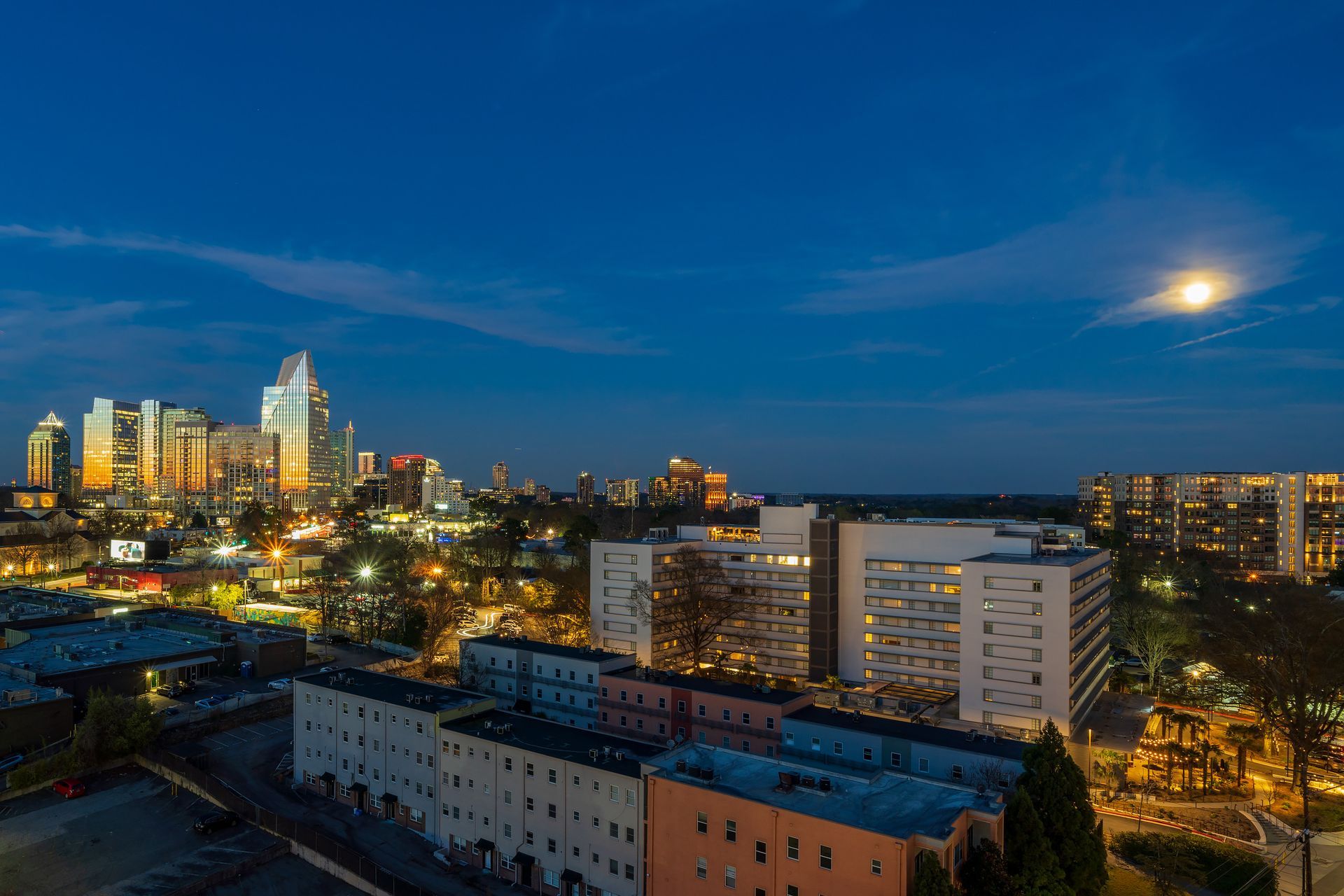 An aerial view of a city at night with a full moon in the sky.