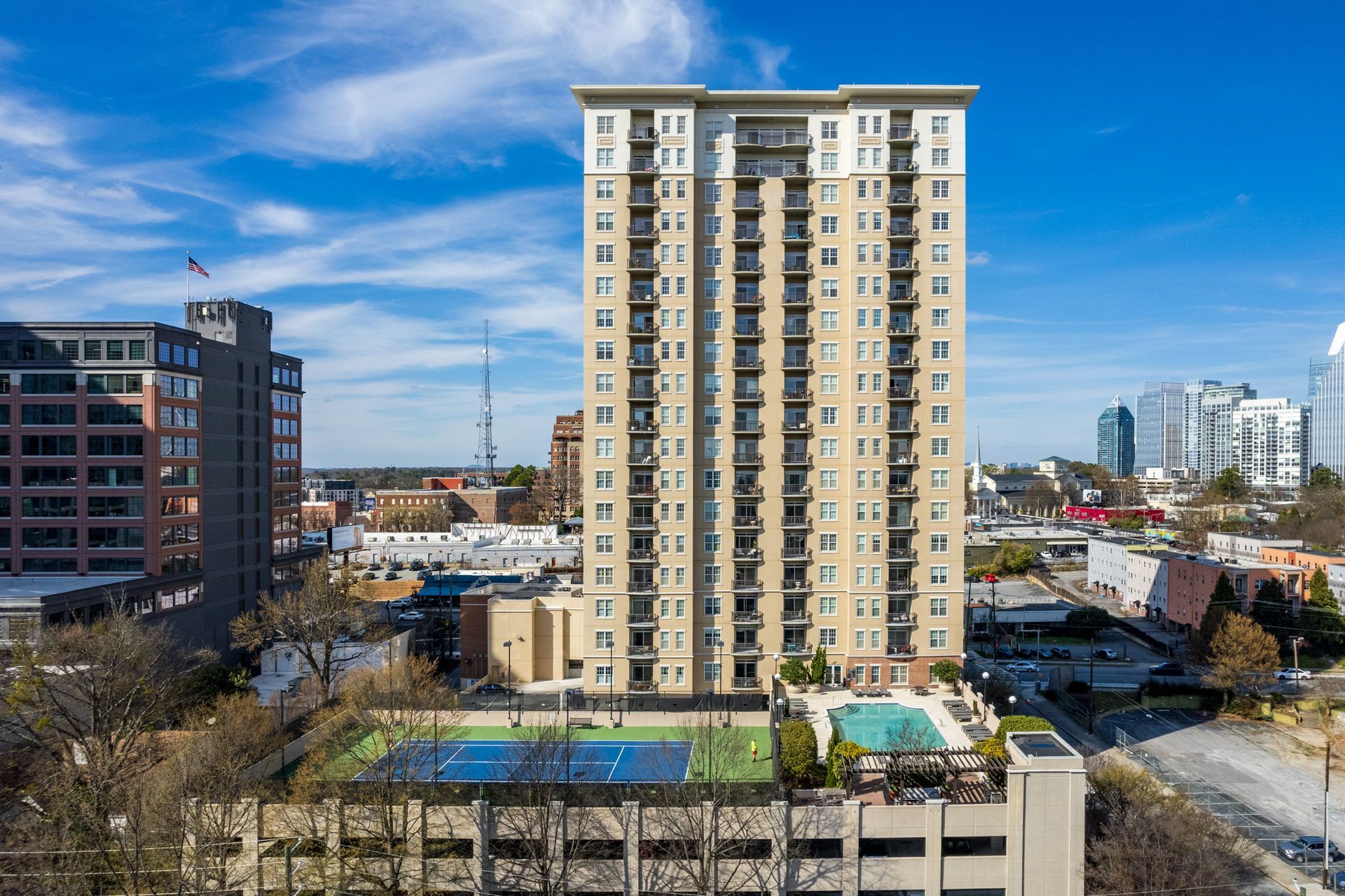 An aerial view of a tall building with a tennis court in front of it.
