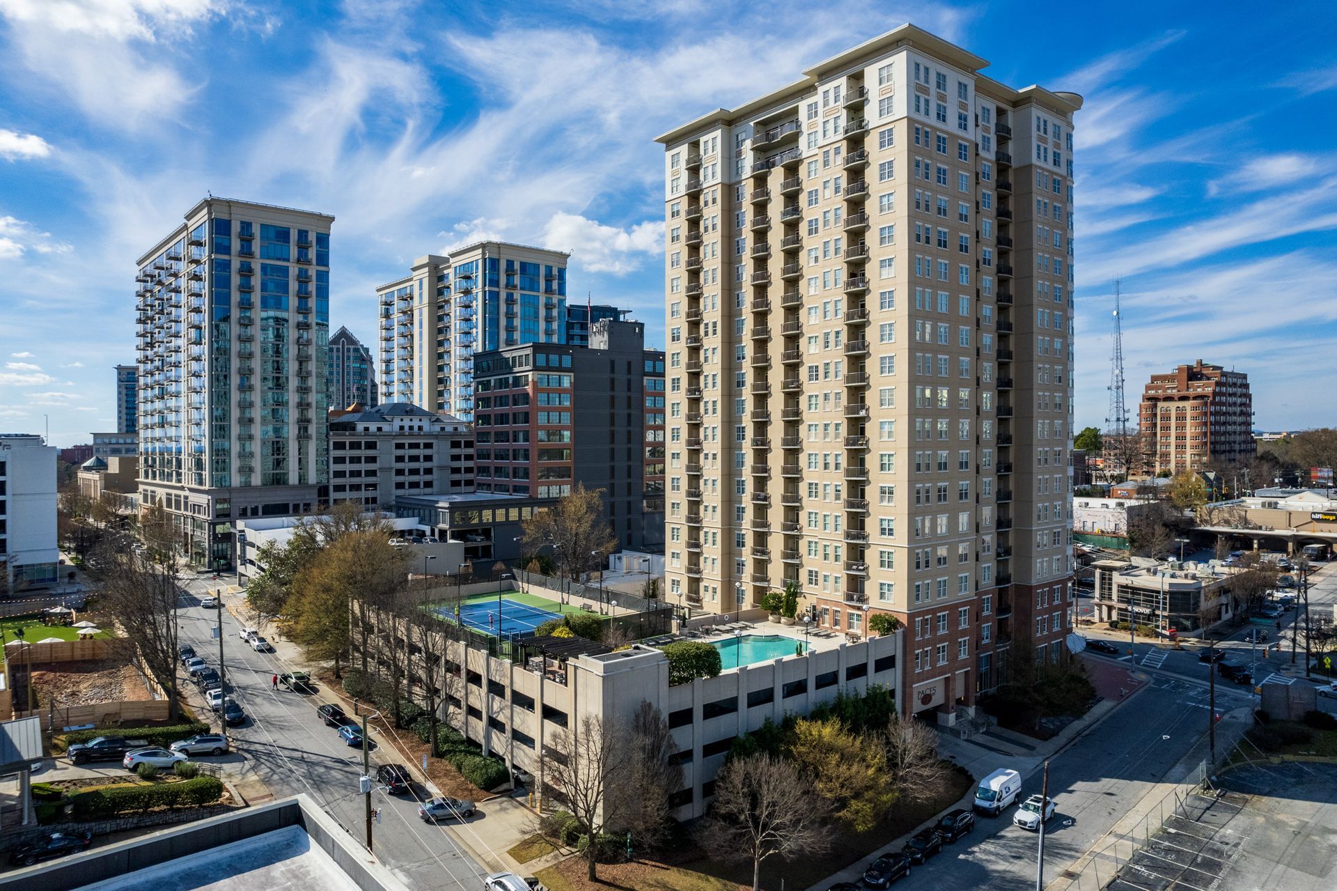 An aerial view of a large building with a pool in the middle of a city.