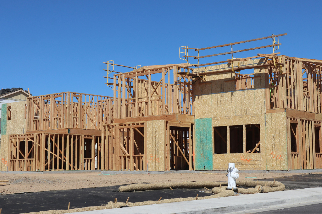 Wood-framed building under construction against a clear blue sky.
