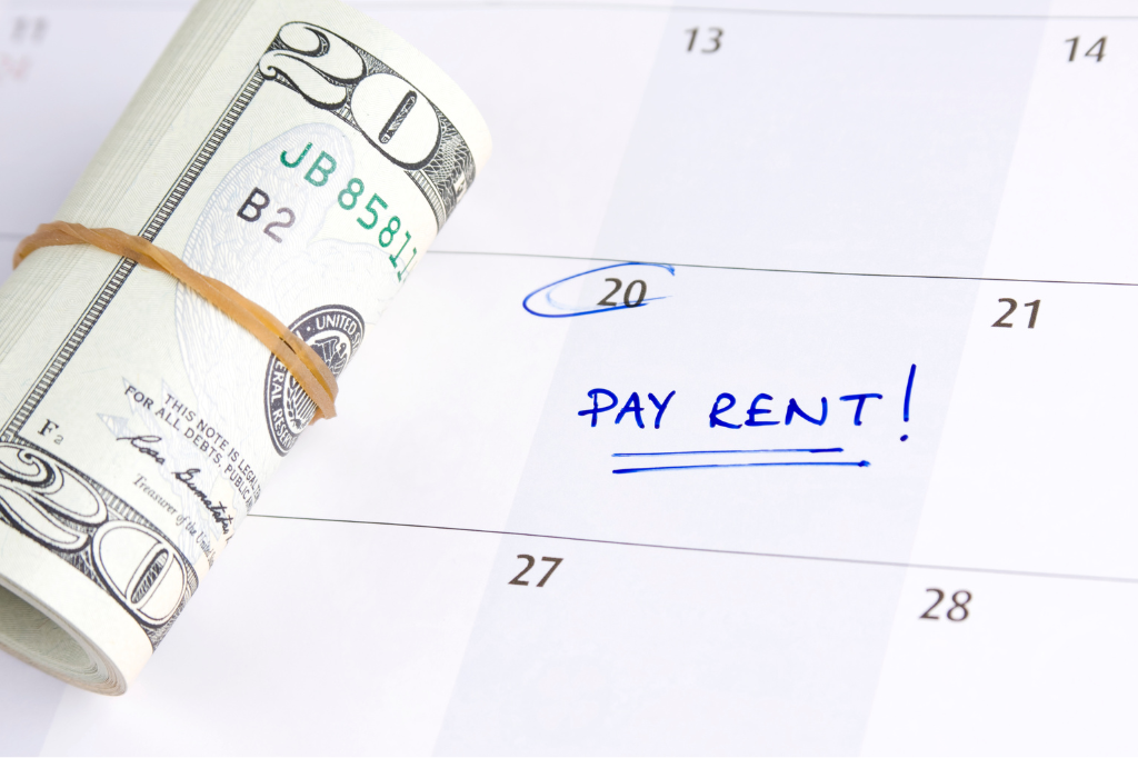 Rolled stack of cash next to a calendar with the 20th circled and