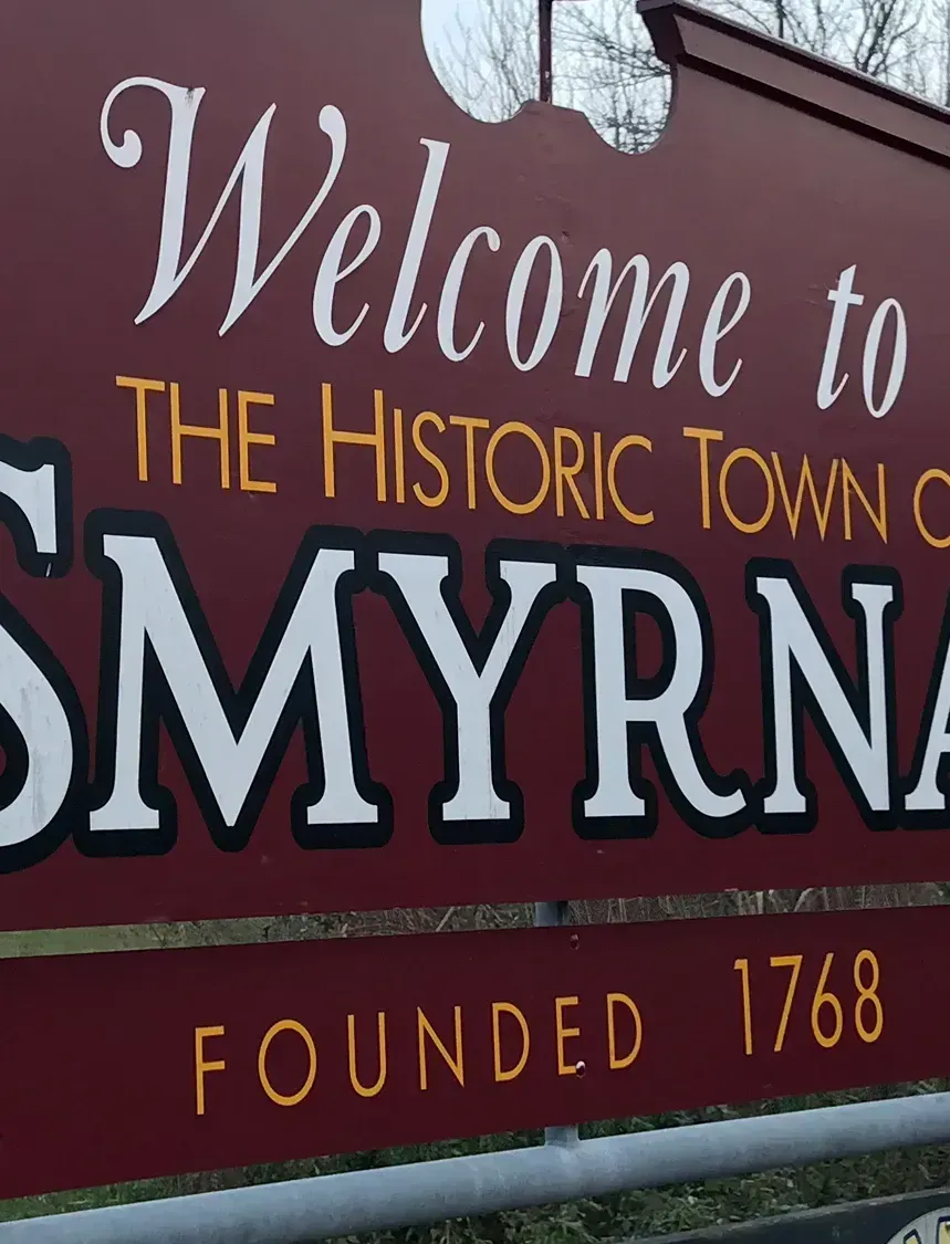 A red sign that says welcome to the historic town of smyrna
