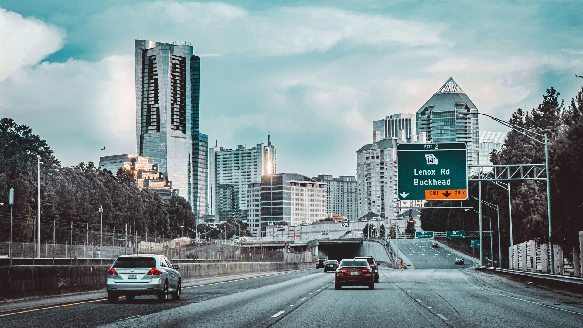 A car is driving down a highway in front of a city.