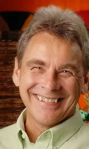 A man in a green shirt is smiling for the camera.
