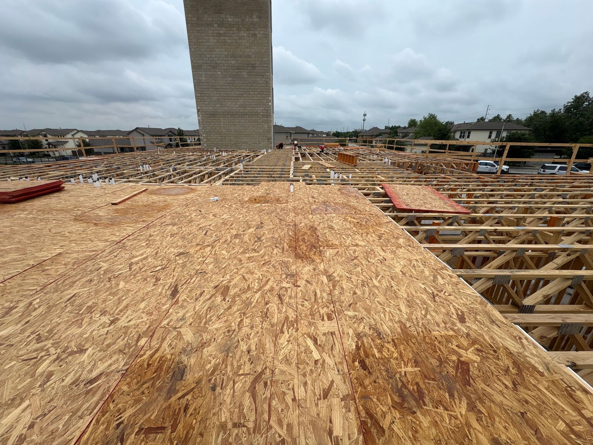 Construction site with wooden floor framing and a tall concrete column under an overcast sky