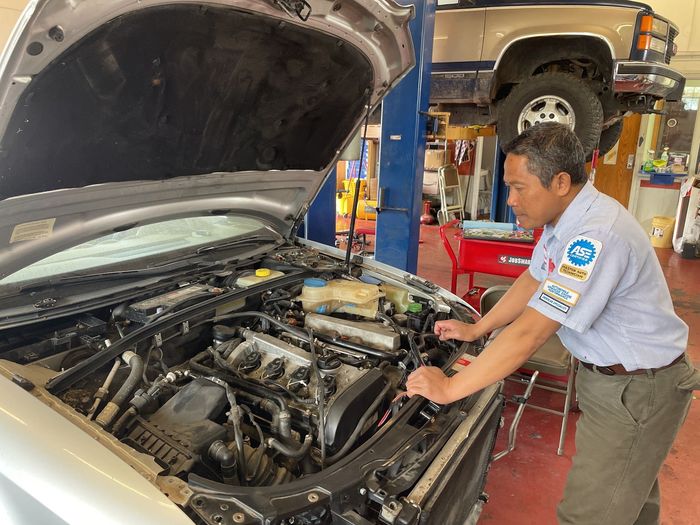 Mechanic working on an open-hood car in an auto repair shop | Alexander’s Automotive, Inc.