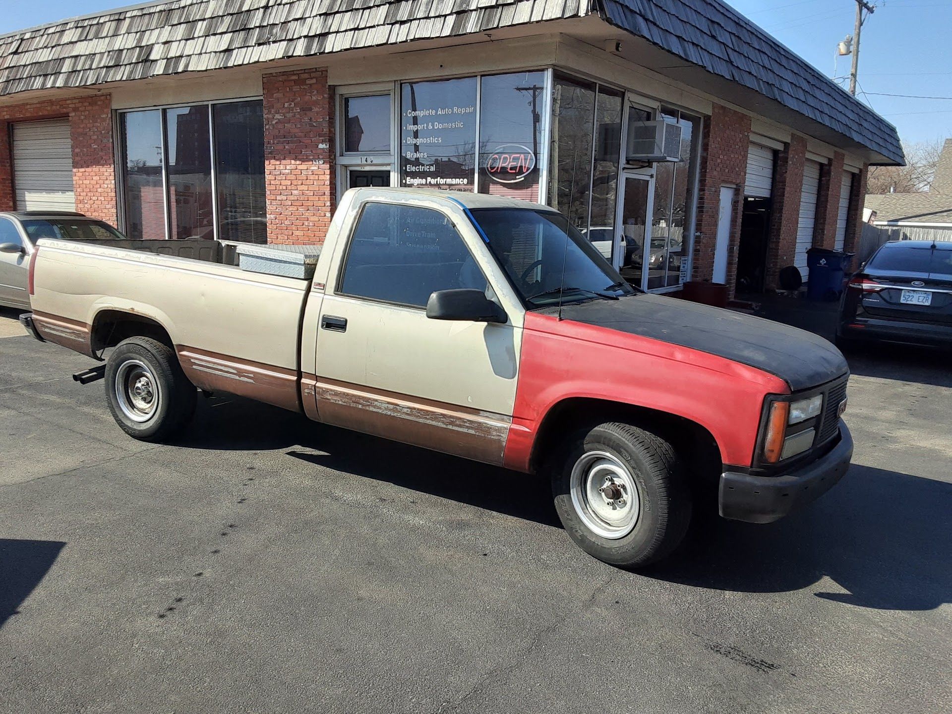 Two-tone beige and red pickup truck parked outside a brick storefront | Alexander’s Automotive, Inc.