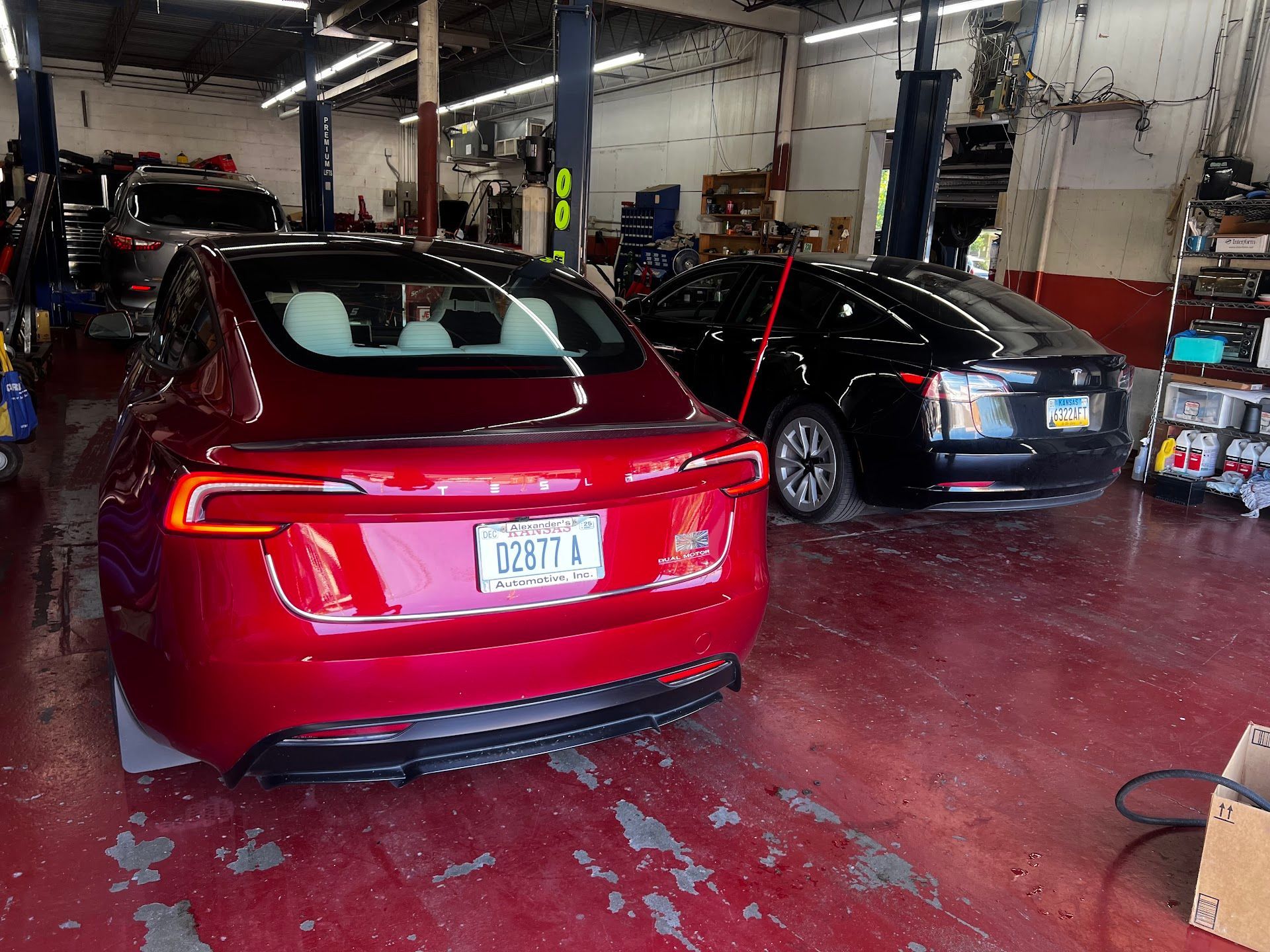 Two cars in an auto repair shop, including a red sedan in the foreground | Alexander’s Automotive, Inc.