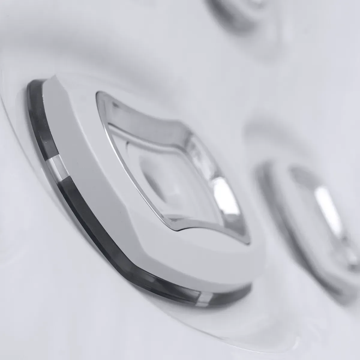 Close-up of white hot tub jets with silver detailing, set into a curved surface.