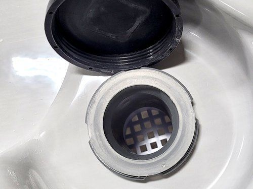 Black and white filter with the parts of a drain pipe against a white background. Open pipe with a filter.