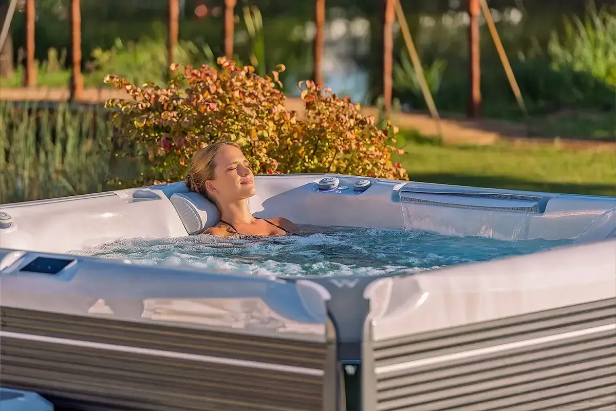 Woman relaxing in a hot tub outdoors, eyes closed, enjoying bubbles.