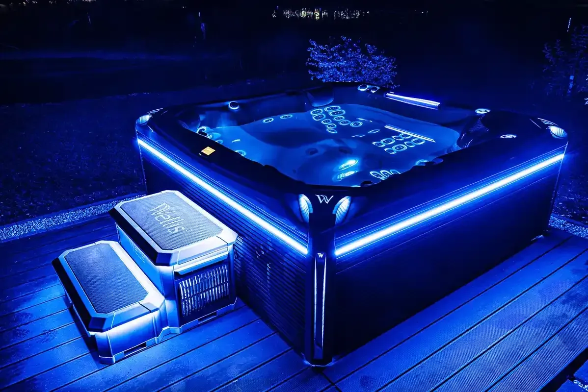 Lit-up hot tub with blue LED lights in an outdoor setting at night. Steps are also illuminated.