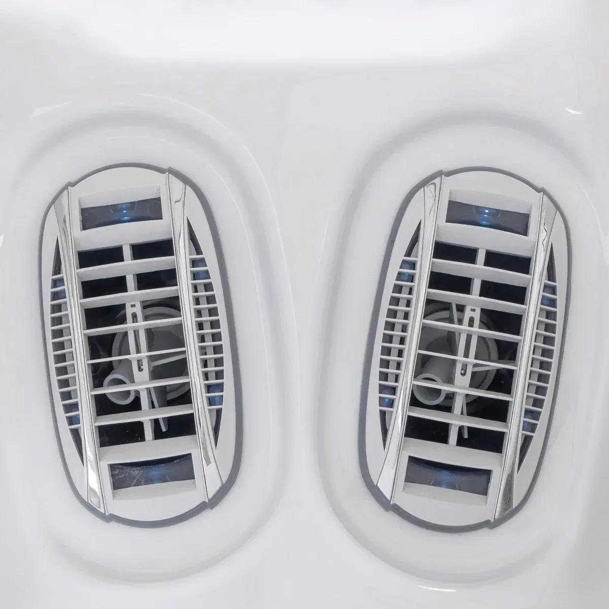 Two white hot tub jets with a gray grid design.