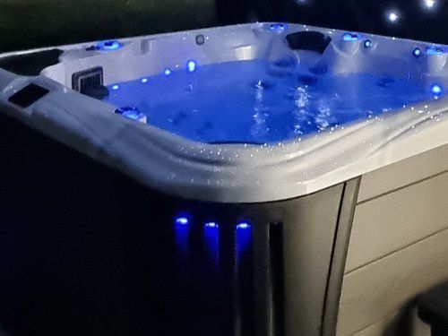 Lit hot tub at night with blue lights illuminating the water and exterior.