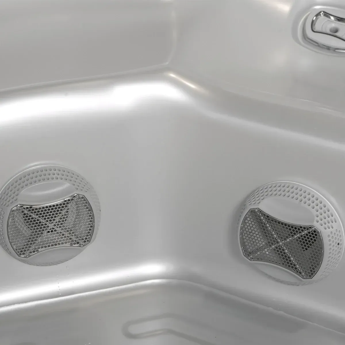 Close-up of the interior of a hot tub with two round, metal-screened jets embedded in the side.