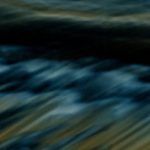 Dark ocean waves, blue and gold tones.