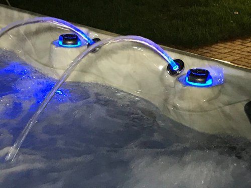 Bubbling hot tub with illuminated blue fountains and jets.