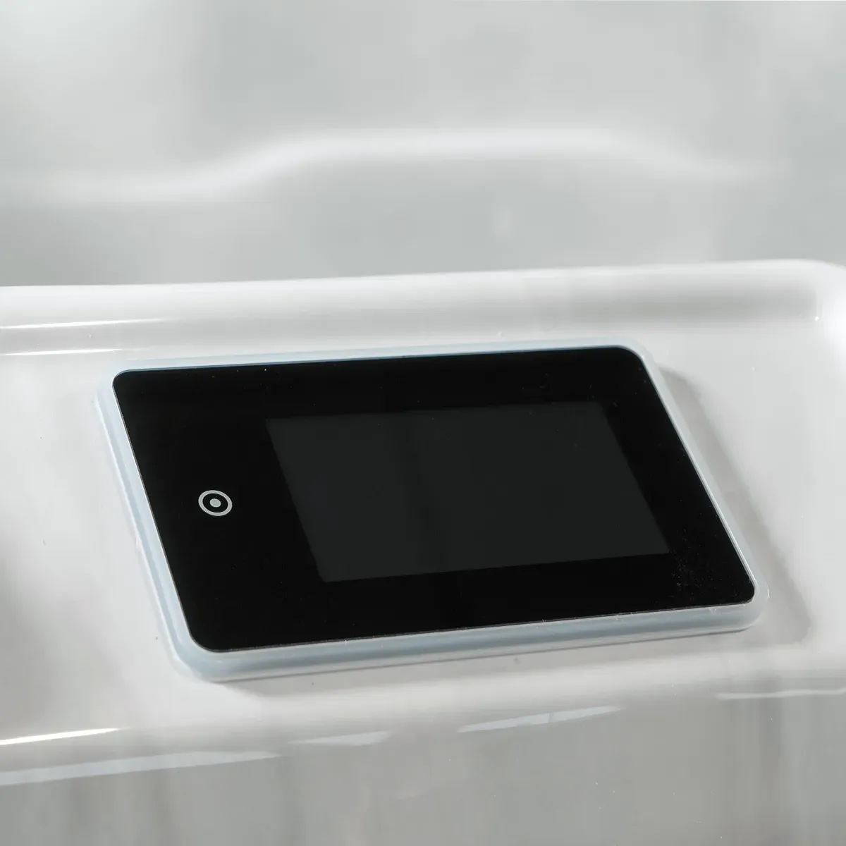 Black and white control panel with a small screen and an illuminated circle symbol on a white surface.