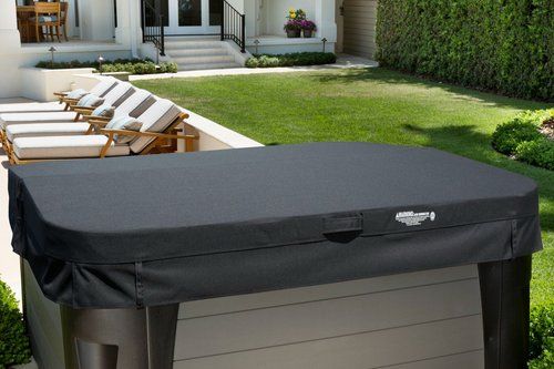 Hot tub with a black cover in a backyard setting.