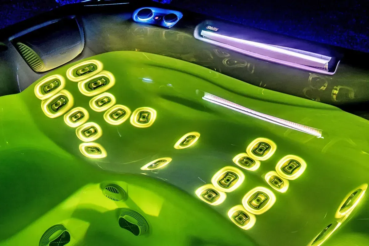 Green hot tub interior with glowing jets and interior lighting.