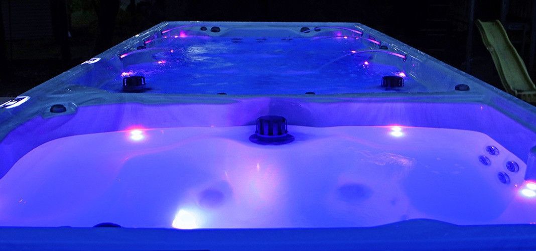 Lit up hot tub with blue and red lights at night.
