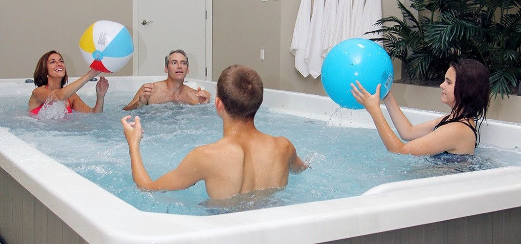 People playing with beach balls in a large indoor spa.