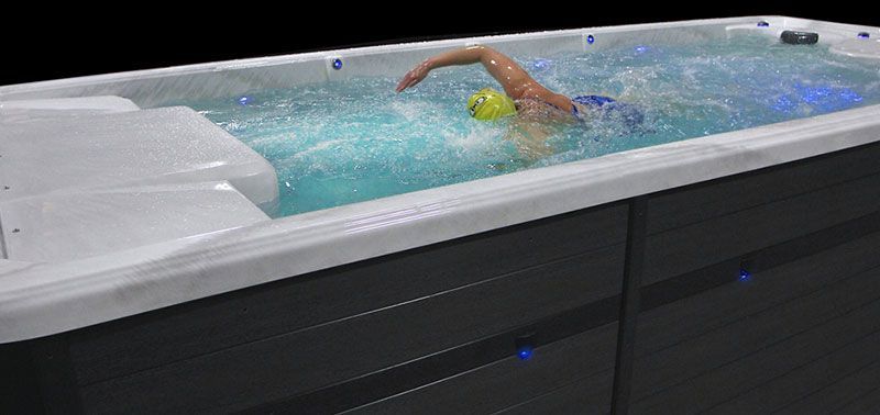 Person swimming in a long, rectangular pool, wearing a yellow swim cap.