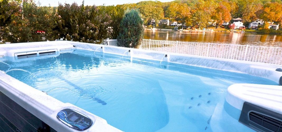 A rectangular pool of blue water with jets. Trees and a lake are visible in the background.
