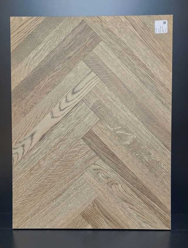 Campione di pavimento in legno a spina di pesce. Venature del legno marrone chiaro e scuro disposte a spina di pesce.