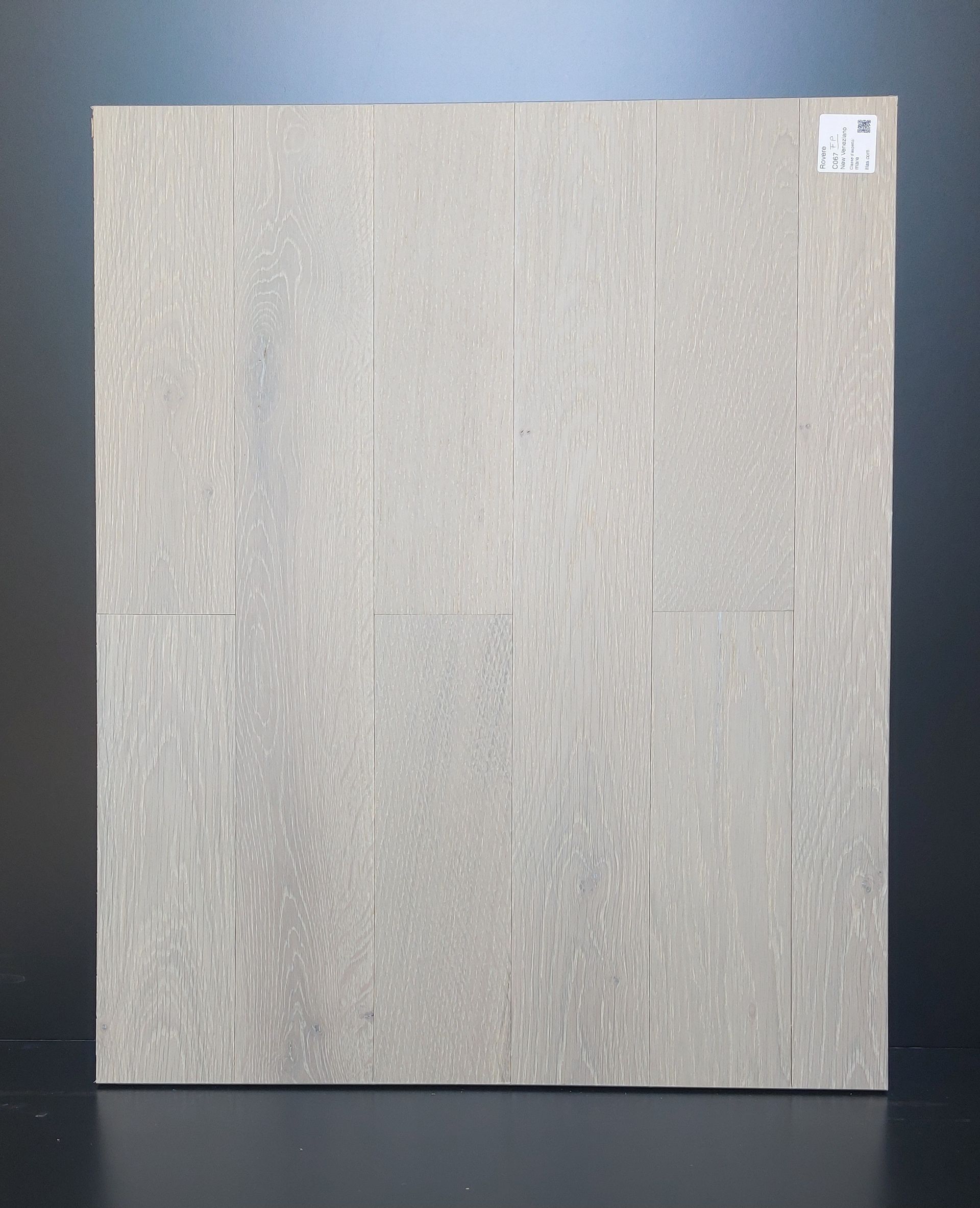 Campione di piastrelle effetto legno grigio chiaro. Listoni verticali con venature variabili e sottili variazioni di colore.