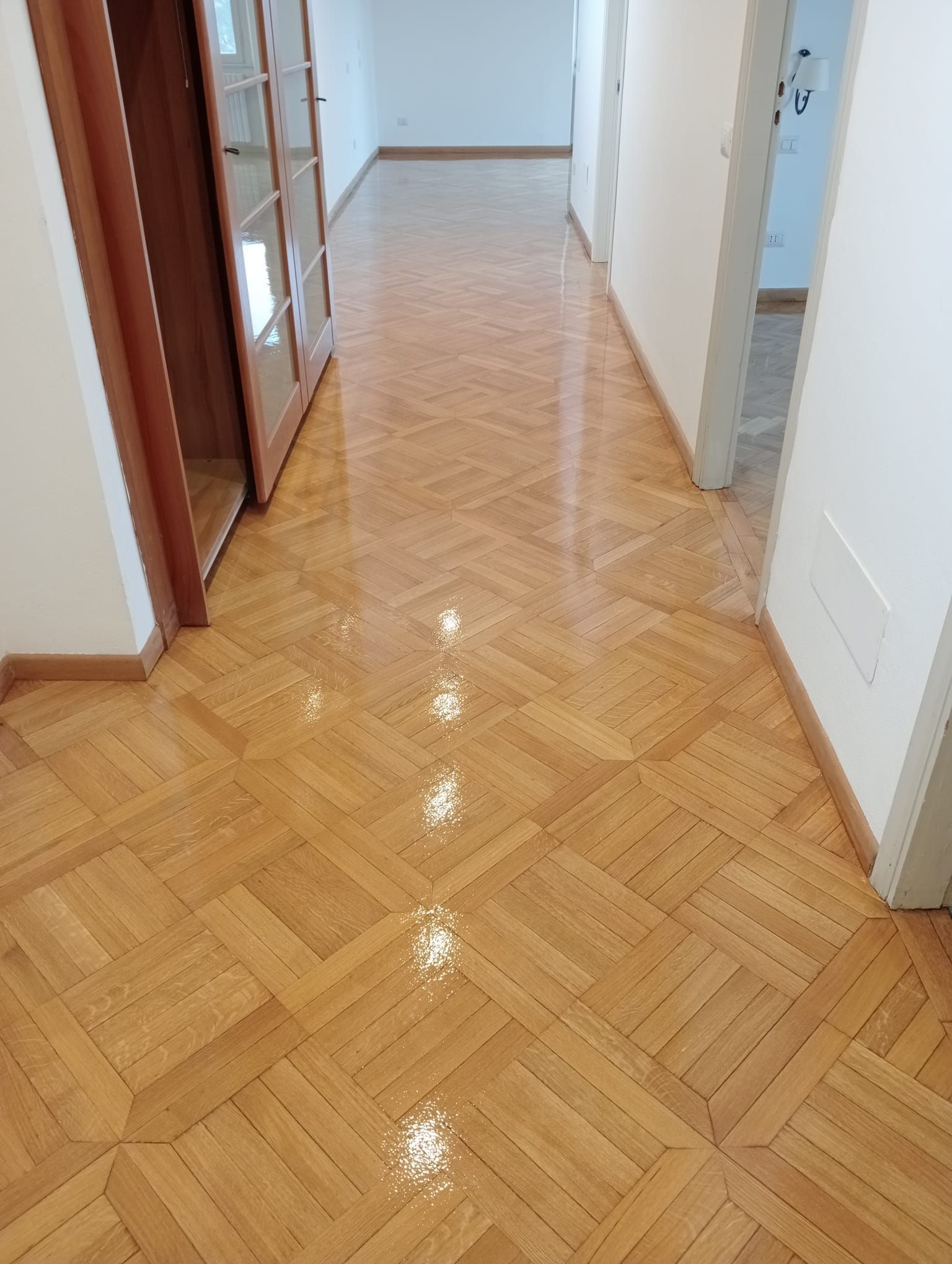 Corridoio con pavimento in parquet lucido.